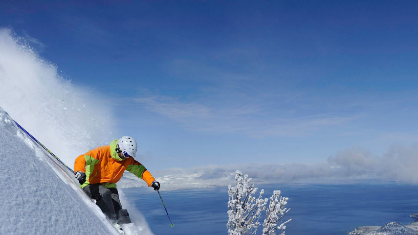 Skier in fresh powder overlooking Lake Tahoe in Heavenly, CA.