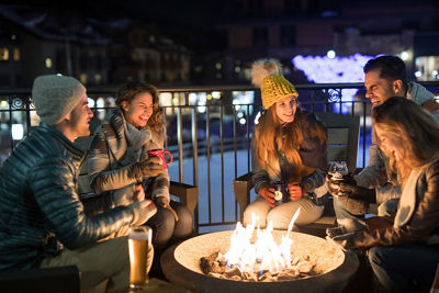Young and Independents enjoy beverages around an outdoor fire pit at Solaris in Vail, CO.