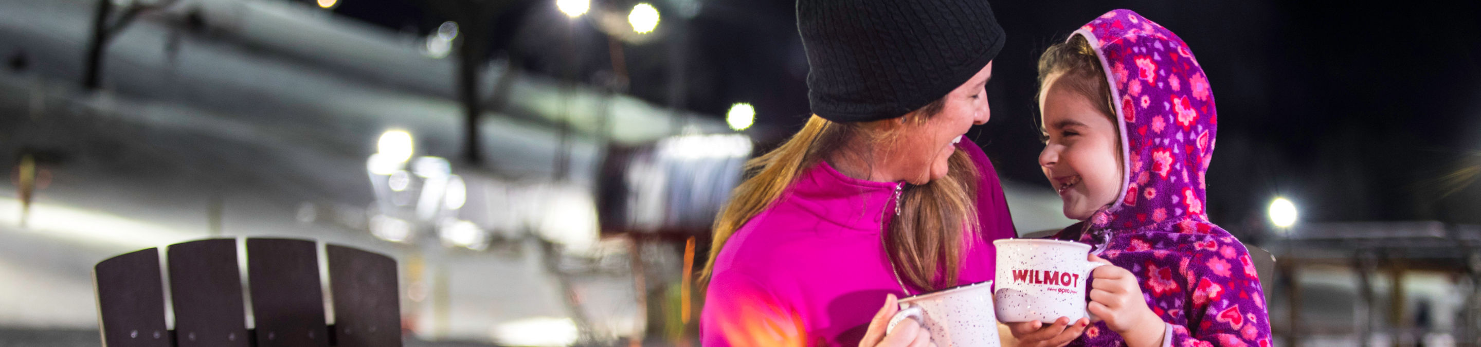 Family relaxes around a firepit at the base of Wilmot Mountain