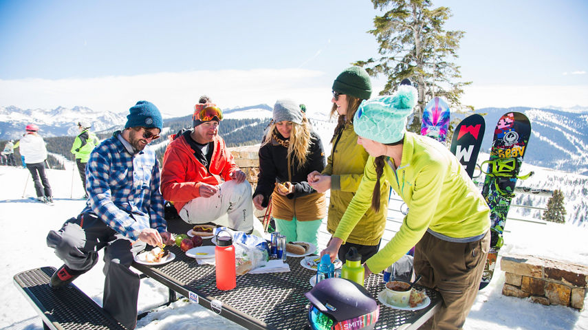 Friends eat and drink at an on-mountain deck in Vail, CO.