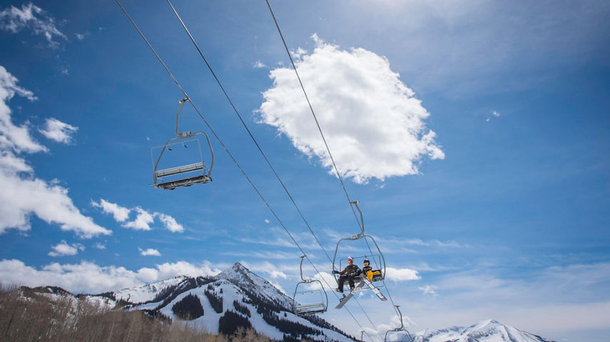 Family rides chairlift under the sun in Crested Butte, CO.