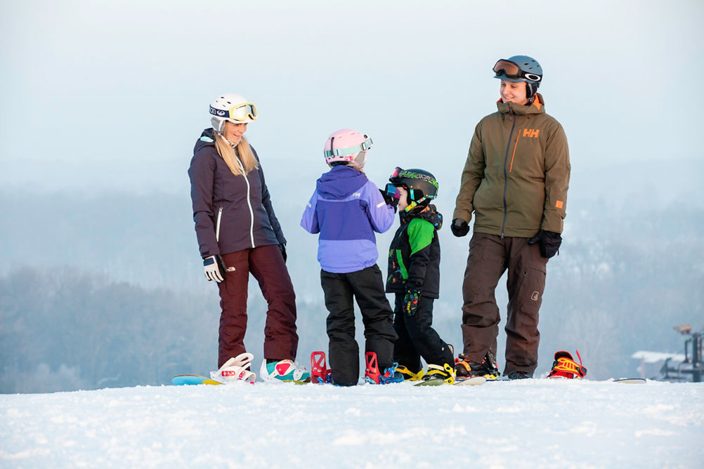 Family gathers at mountain top before snowboarding in Mt. Brighton, MI.