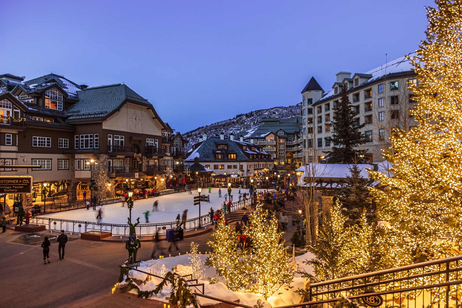Skaters on Beaver Creek Village’s outdoor ice rink surrounded by illuminated trees and village buildings at dusk