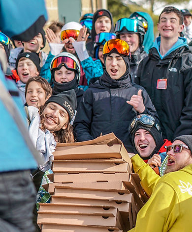Group of Teenage Boys Poses with Stack of Pizzas at Event at Boston Mills