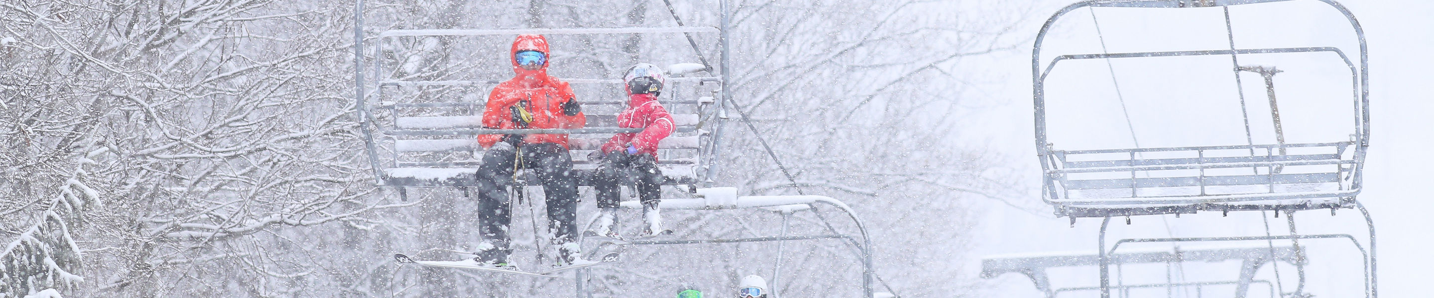 People Ride Minuteman Chair Lift on Snowy Day at Roundtop