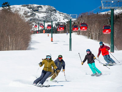 Group of friends ski under the sunshine in Stowe, VT.