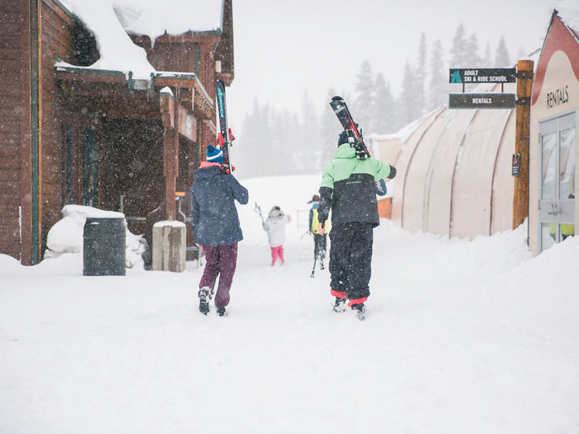Family walking through village to ski in Kirkwood, CA.