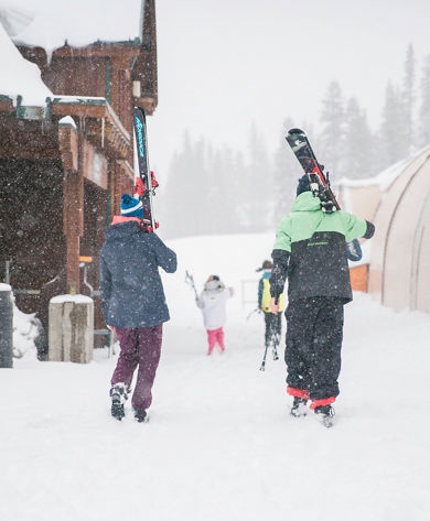 Family walking through village to ski in Kirkwood, CA.