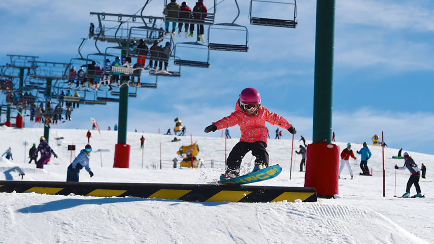 A little girl does snowboarding tricks at the terrain park near Heavenly Valley at Hotham
