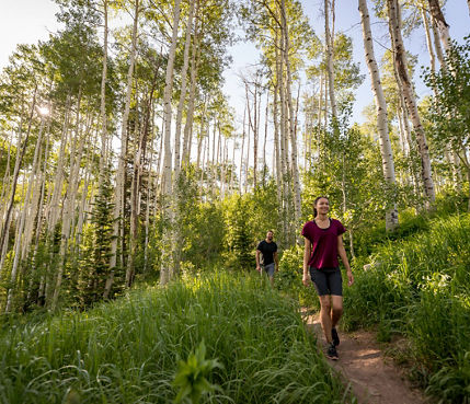 A couple walks on a trail during a summer day at Park City