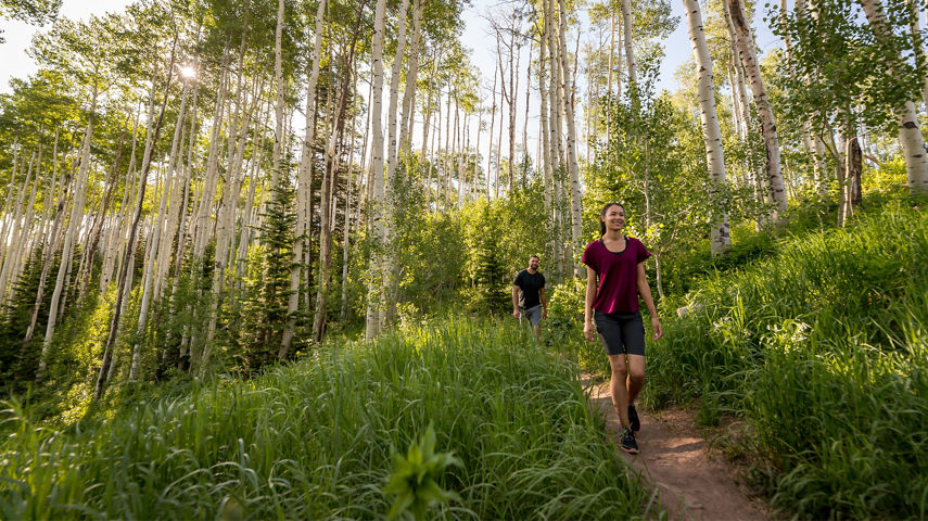 A couple walks on a trail during a summer day at Park City