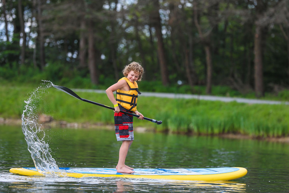 Child Enjoys Stand Up Paddleboarding at Seven Springs