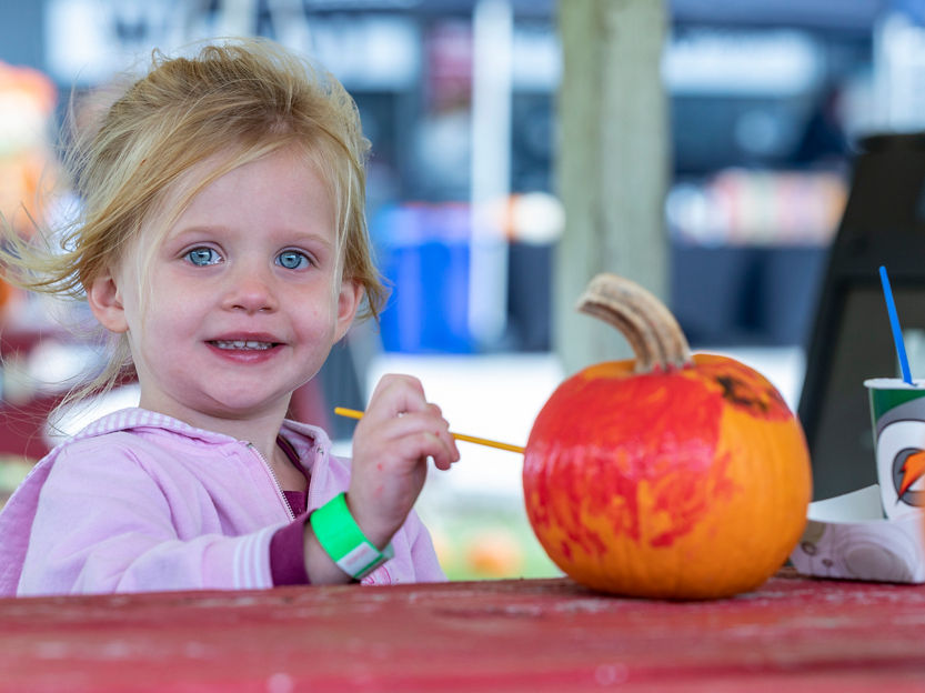 A little girl paints her pumpkin during Fall Festival at Wilmot