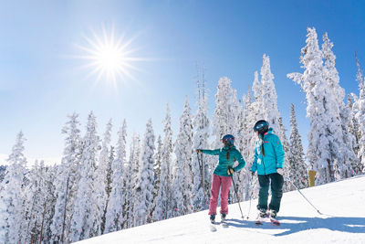 Two women ski North Peak on a blue sky day with fresh snow in Keystone, CO