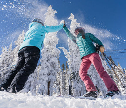 Two women ski North Peak on a blue sky day with fresh snow in Keystone, CO