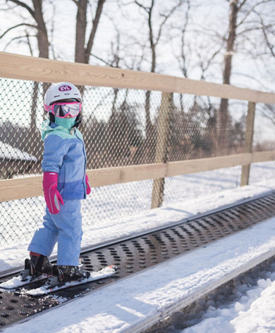 Little Girl Rides the Magic Carpet in the Beginner Area of Alpine Valley