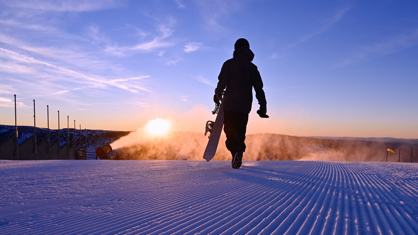 A snowboarder walks on freshly groomed corduroy snow at Heavenly Valley at Hotham