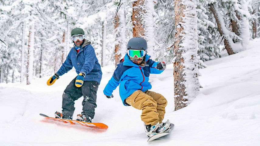 Father and son ride the fresh snow together in Keystone, CO.
