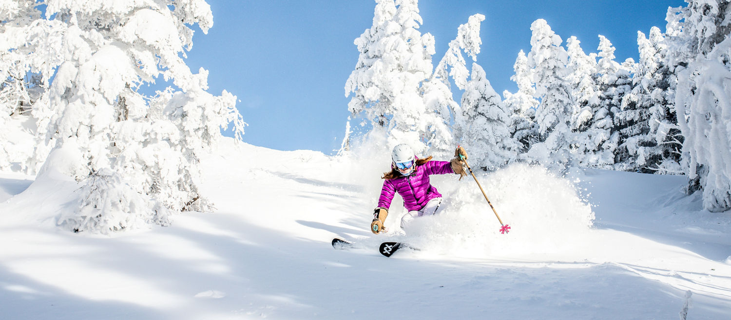 Women Skis Through Snow Covered Trees in Stowe Mountain Resort