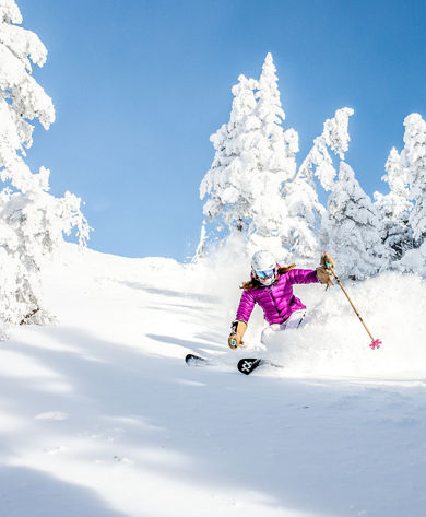 Women Skis Through Snow Covered Trees in Stowe Mountain Resort