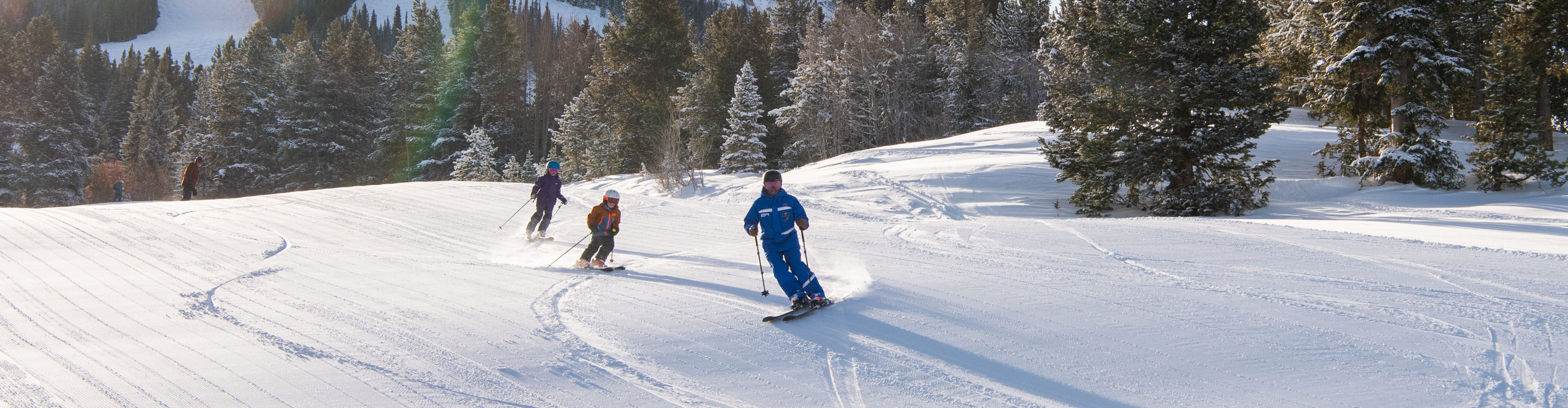 Kids ski school group skiing with instructor at Crested Butte
