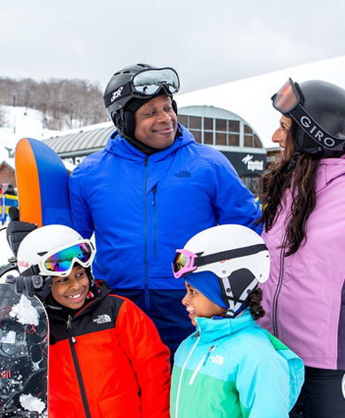 Family with Snowboards Smiling in Front of Bluebird Express