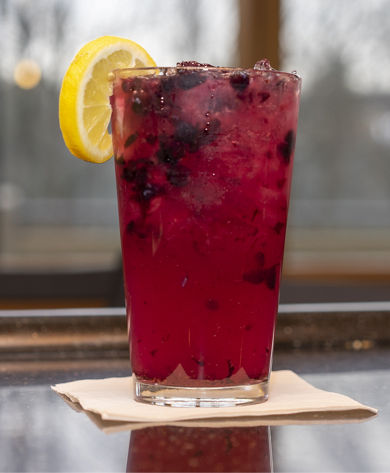 Mixed drink with berries and lemon at Solstice Bar