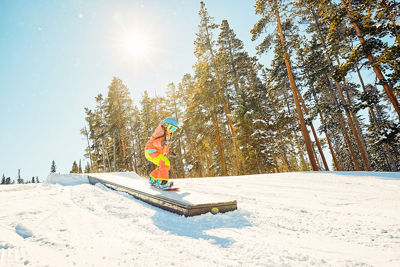 Young snowboarder riding a box in terrain park at Keystone Resort