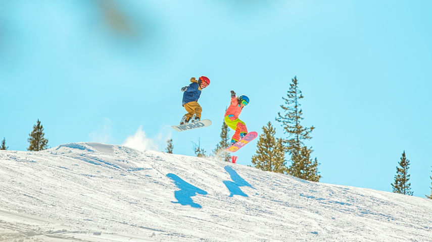 Two snowboarders catching air in terrain park at Keystone Resort