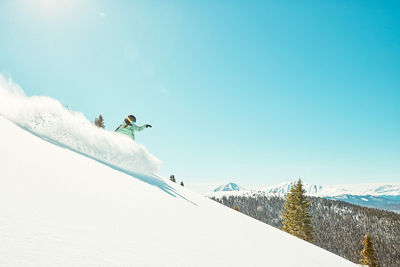 Snowboarder slashing snow with view in background at Keystone Resort