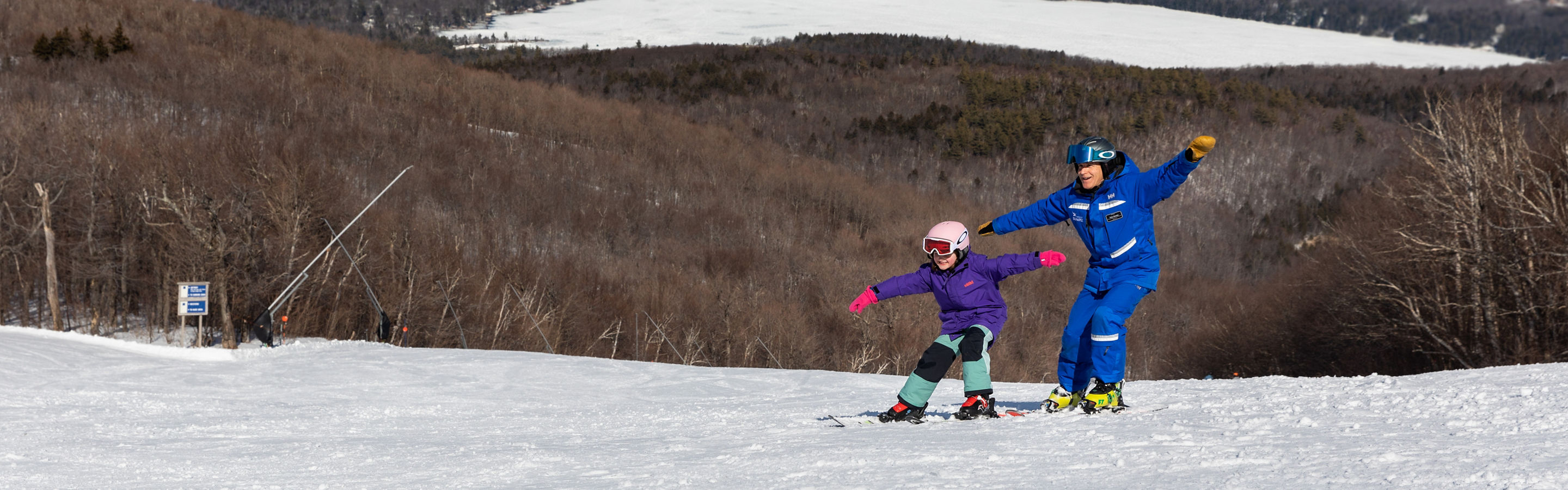Child Skiing with Instructor with View of Lake at Mount Sunapee
