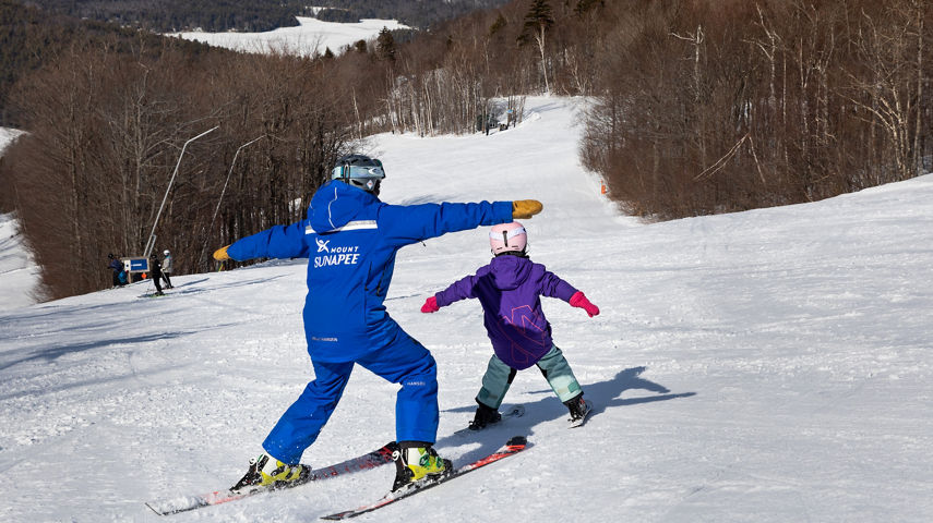 Child Skiing with Instructor with Arms Out at Mount Sunapee