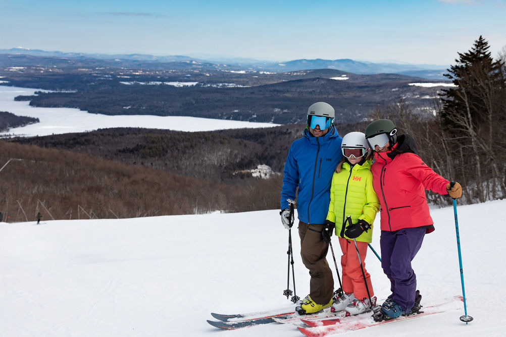 Two Parents and One Child Posing with View of Lake  at Mount Sunapee