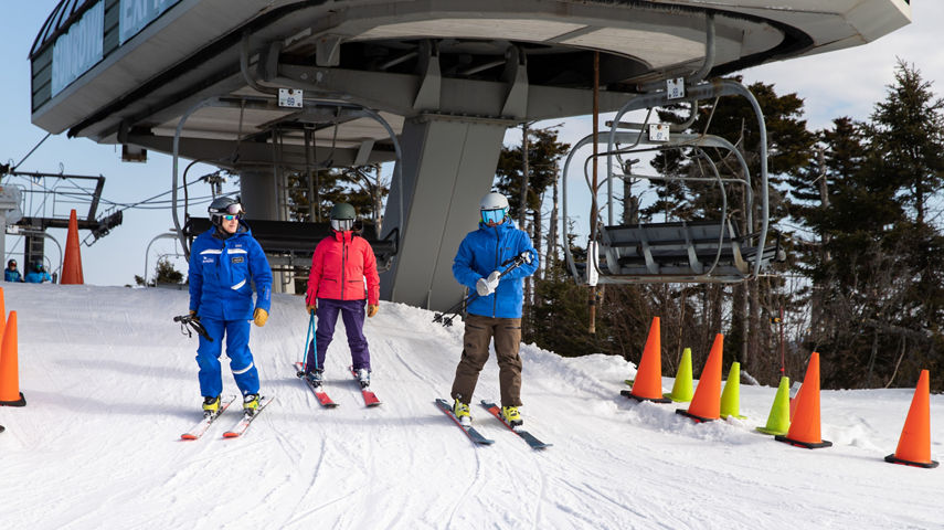 Two Adults and Instructor Getting Off Lift  at Mount Sunapee
