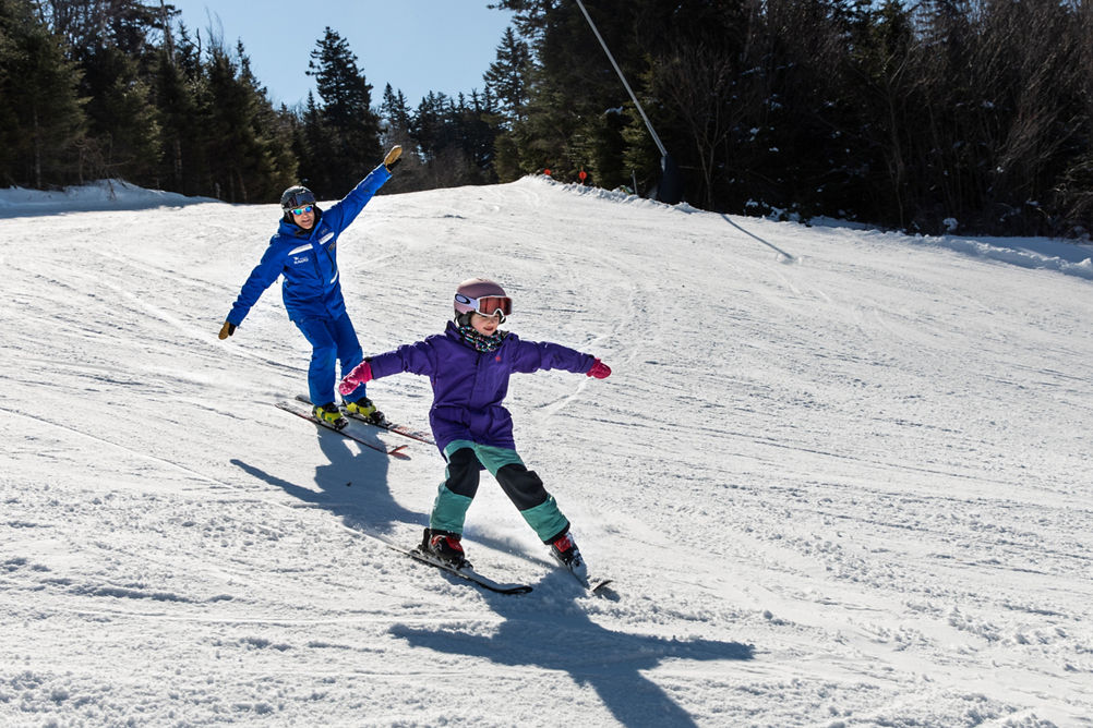 Child Skiing with Instructor with Arms Out  at Mount Sunapee