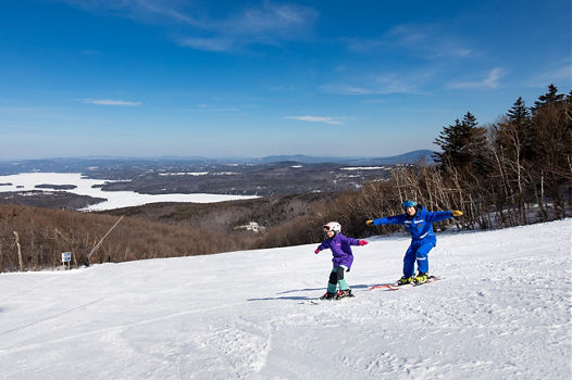Child Skiing with Instructor with Arms Out  at Mount Sunapee