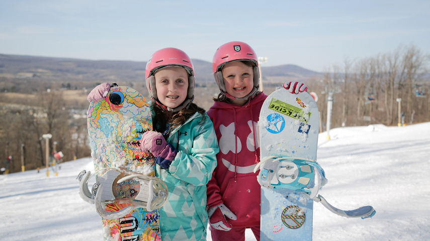 Two Little Girls Pose with Snowboards at Event at Liberty Mountain
