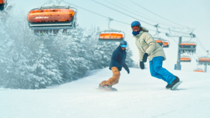 Man and Woman Snowboarding Under Sunburst Six at Okemo