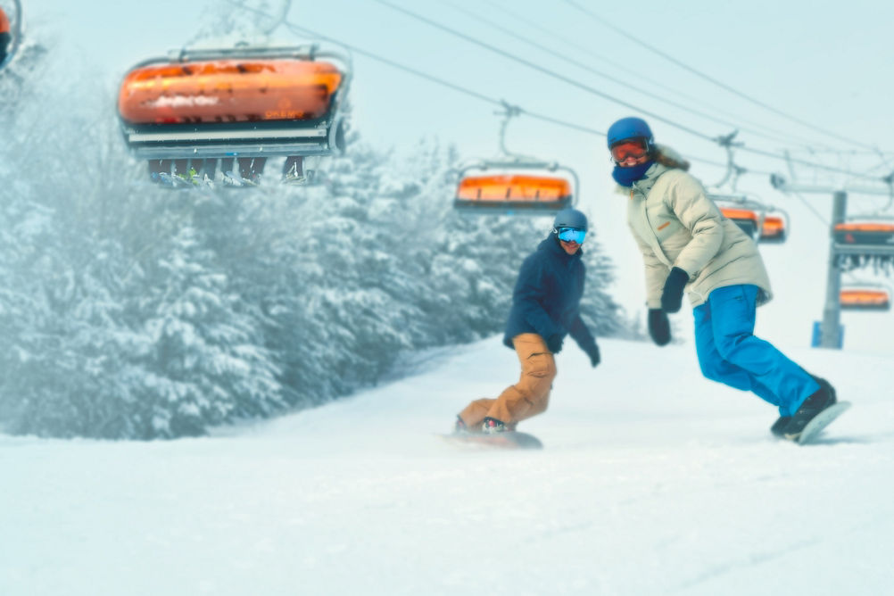 Man and Woman Snowboarding Under Sunburst Six at Okemo