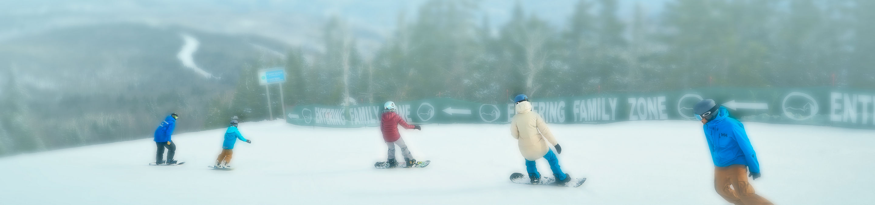 Family snowboarding Down Trail Following Instructor at Okemo