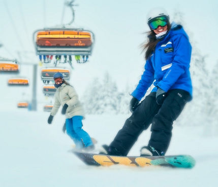 Instructor Leading Woman Snowboarder Under Sunburst Six at Okemo