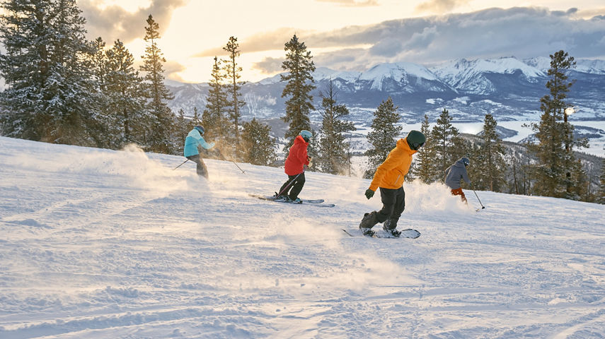Friend group riding downhill during sunset at Keystone Resort