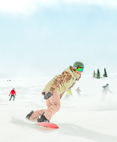 Snowboarder smiling in fresh snow while cat skiing at Keystone Resort