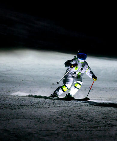 Skier dressed as an astronaut skis at night on Crotched Mountain