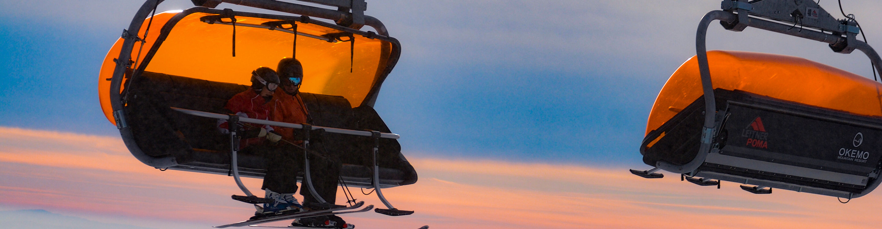 Guests ride the orange chairlift at Okemo
