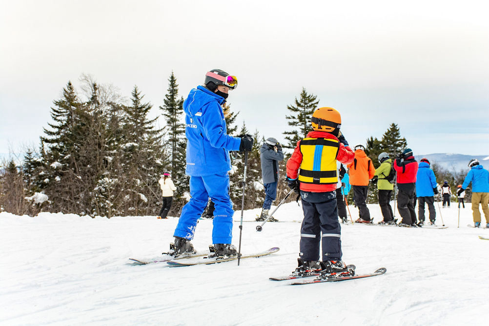 An instructor teaches a child how to ski at Okemo