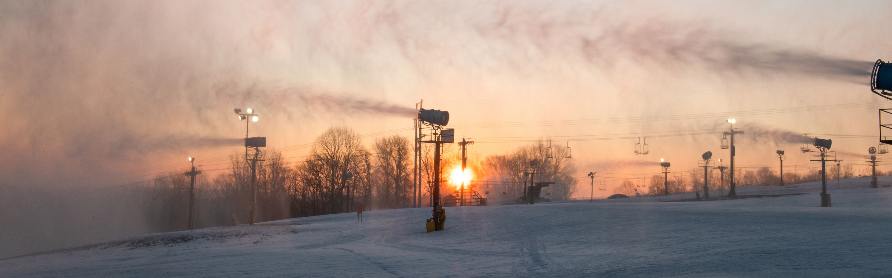 Sunset on the slopes with snow guns on during a winter day at Paoli Peaks