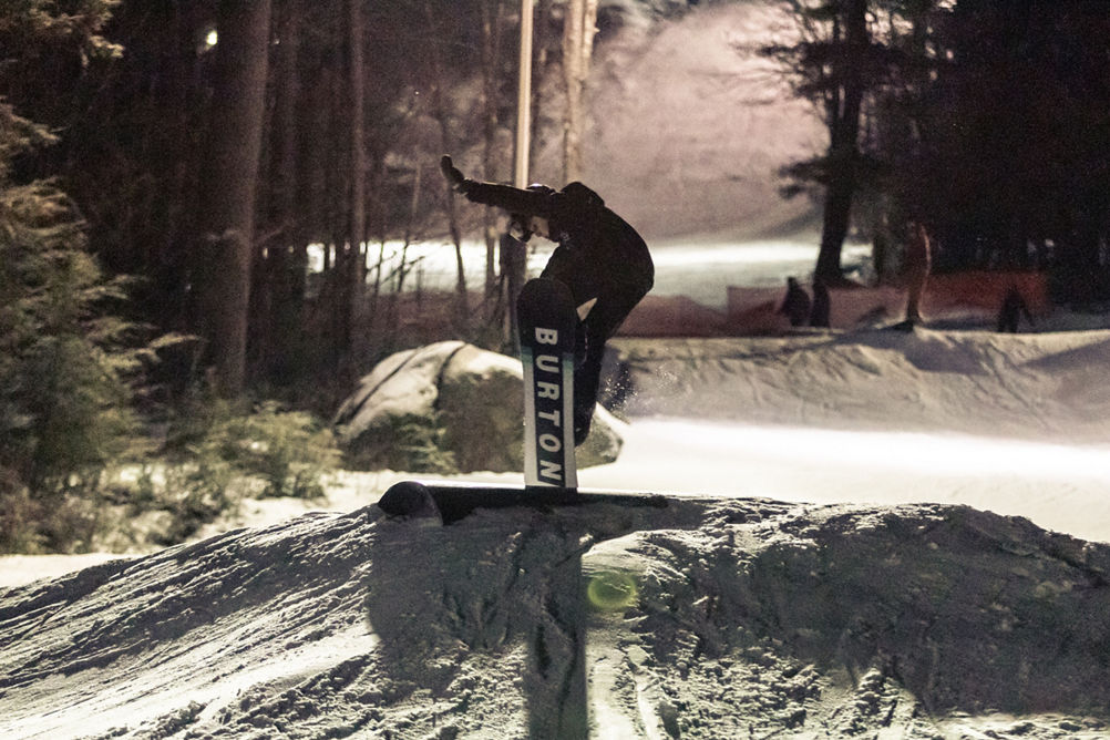 A snowboarder enjoys the terrain park at night on Crotched Mountain