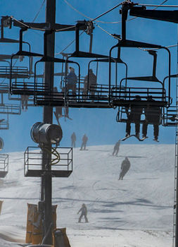 Skiers and riders coming down slopes with guests on chairlift overlooking at Paoli