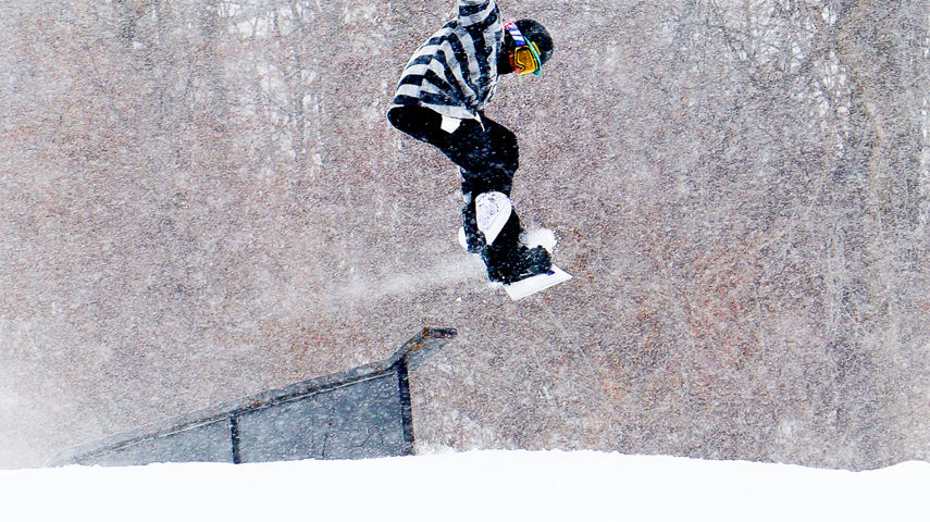 Snowboarder launches from a terrain park feature on a snowy day at Snow Creek